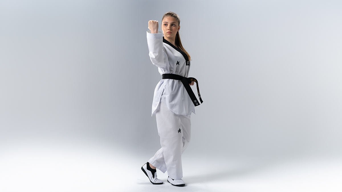 Atleta brasileira faixa preta em postura de poomsae, dobok Sulsport com bandeira do Brasil